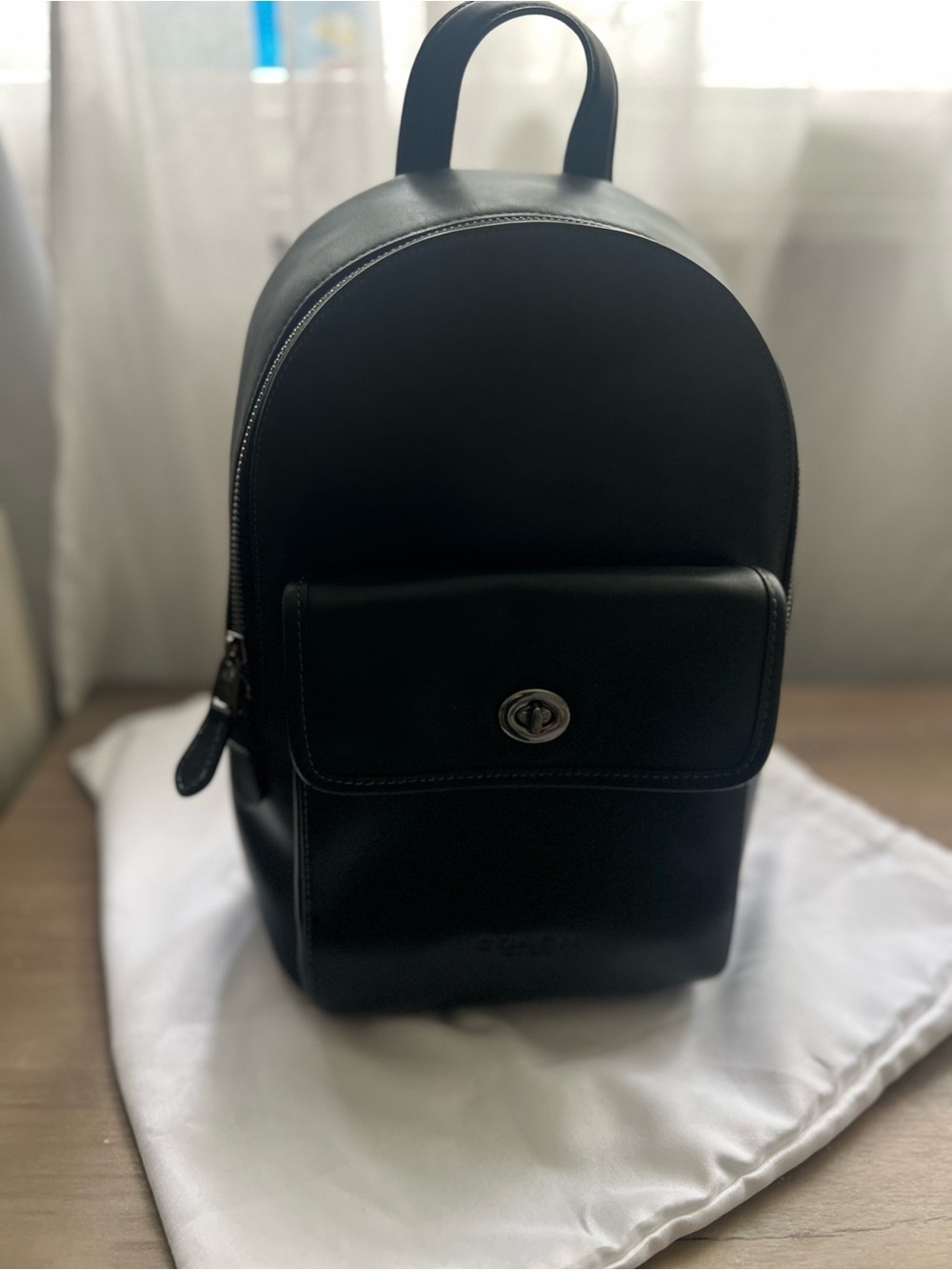 Coach Black Leather Turnlock Sling Pack in black leather.